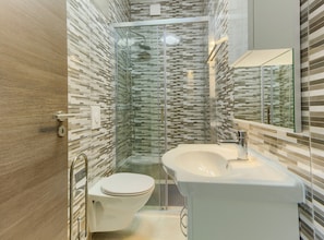 A modern bathroom with a glass shower enclosure, a toilet, and a sink with a mirror above it.