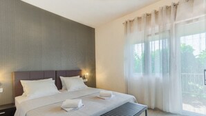 Ein modernes Schlafzimmer mit einem großen Bett, einer Bank und Blick auf Grün.