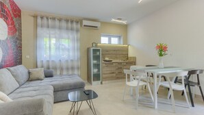 Ein modernes Wohnzimmer mit einer Couch, einem Glastisch und einem Essbereich mit Tisch und Stühlen.