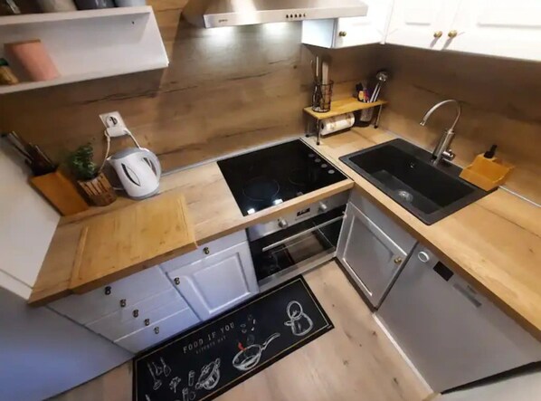 Une cuisine de taille réduite, équipée d’une cuisinière, d’un évier et d’un four.
