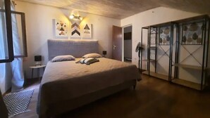 Une chambre à coucher comprenant un lit, une table de chevet, un luminaire fixé au mur et une armoire.
