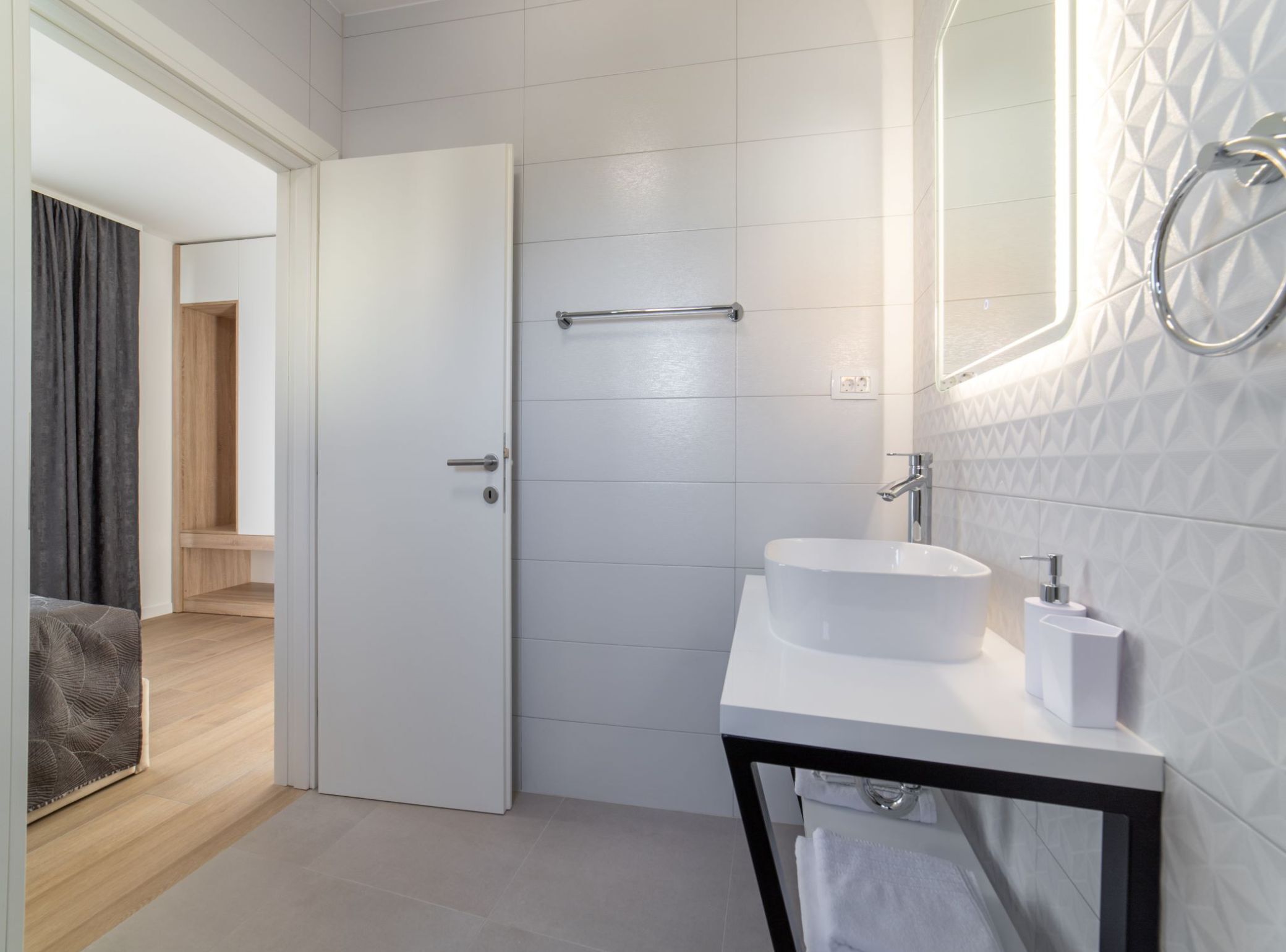 A modern bathroom with a white sink, a mirror, and a towel rack.