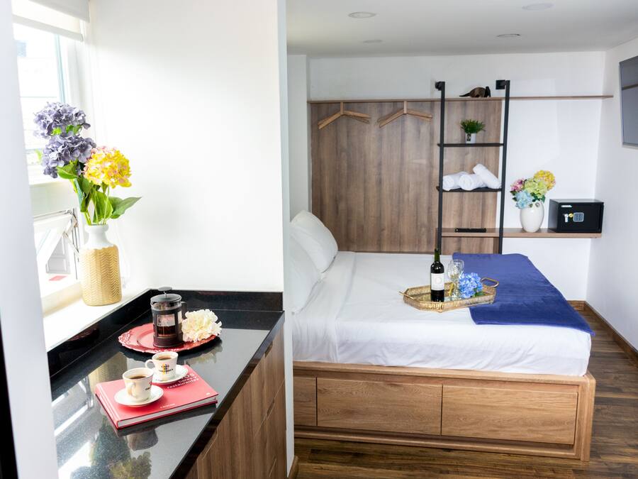 Een hotelkamer met een bed, nachtkastje en een wandplank.