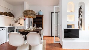 A modern kitchen with white cabinetry, a dining table with chairs, and a hanging light fixture.