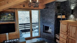 Une pièce chaleureuse avec une cheminée, des meubles en bois et une grande fenêtre donnant sur un paysage magnifique.