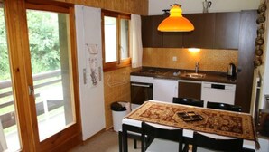 Une cuisine chaleureuse avec des meubles de rangement en bois, une table à manger avec des chaises et un luminaire suspendu.
