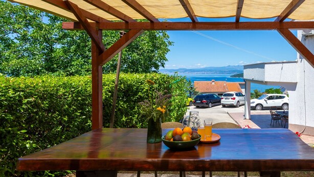 An outdoor table with a view of the sea and parked cars. - Apartment Anivija (Omisalj)