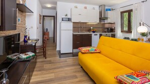 A compact living space with a kitchen, dining area, and a bright yellow sofa. - Apartment Anivija (Omisalj)
