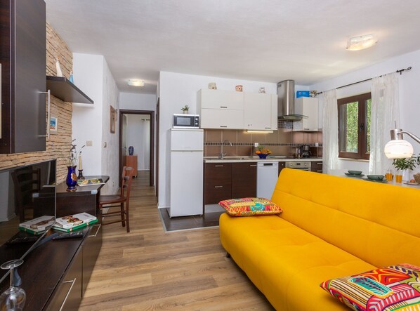Un espacio habitable compacto con cocina, comedor y un sofá amarillo brillante.