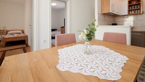 A wooden dining table with a lace tablecloth and a vase of flowers. - Cozy Downtown Trogir Apartment With Balcony (Trogir)
