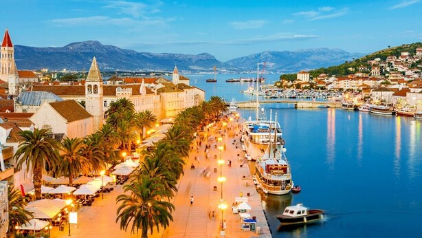 A waterfront promenade with palm trees, street lamps, and boats docked at a marina. - Cozy Downtown Trogir Apartment With Balcony (Trogir)