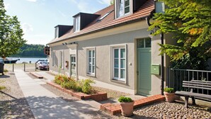 A two-story building with a sloped roof, a green door, and a bench outside. - Cozy vacation apartment "Claire" directly at the harbor of Rheinsberg (Rheinsberg)