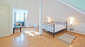 A bedroom with a bed, a chair, a small table, and a lamp. - Cozy vacation apartment "Claire" directly at the harbor of Rheinsberg (Rheinsberg)