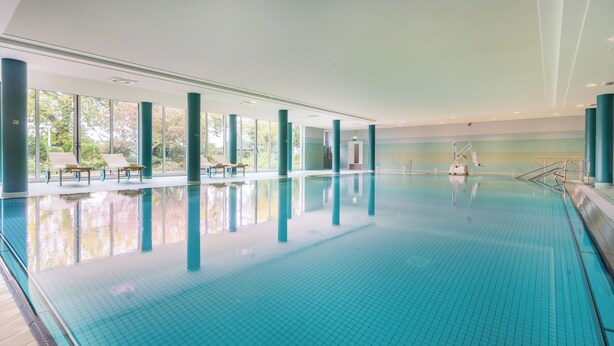 An indoor swimming pool with clear blue water, large windows, and sun loungers. - Cozy vacation apartment "Claire" directly at the harbor of Rheinsberg (Rheinsberg)