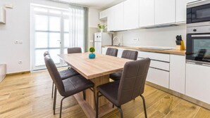 Una cucina moderna con mobili bianchi, un tavolo da pranzo in legno e quattro sedie.