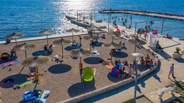 Una spiaggia con ombrelloni, lettini e un'area piscina.