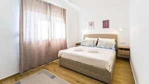 Una camera da letto con un letto, un comodino, una lampada a muro e una finestra con tende.