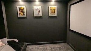 A room with a projector screen, a bed, and three framed pictures on the wall. - Modern Home From Home With Cinema - Elm Tree House (Leicester)