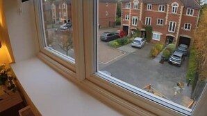 A view from a window of a residential area with a brick house, parked cars, and a clear sky. - Modern Home From Home With Cinema - Elm Tree House (Leicester)