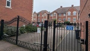 A gated residential area with brick buildings and a sign indicating a private community. - Modern Home From Home With Cinema - Elm Tree House (Leicester)