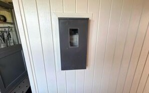Une porte dotée d’une petite fenêtre, de panneaux blancs et d’une plaque métallique.