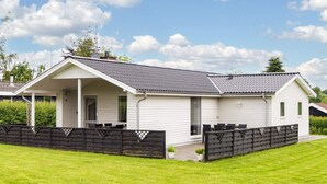 A single-story mobile home with a covered patio, a fenced yard, and a clear sky. - 4 Star Holiday Home in Hejls (Hejls)