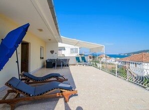 Un balcone con lettini, un tavolo e sedie, con vista sulla costa.