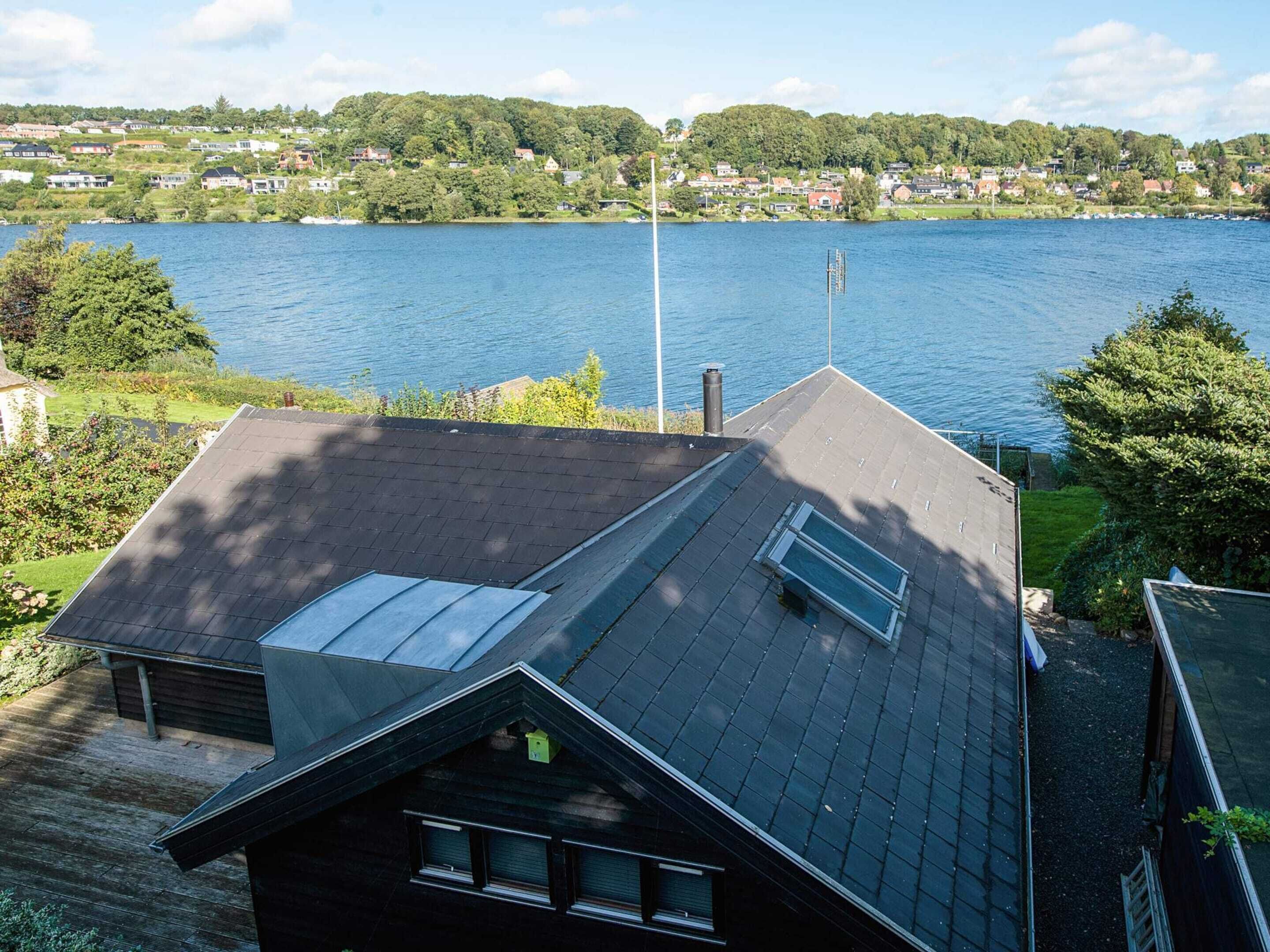 Une maison avec un toit en pente, une cheminée visible et une fenêtre.