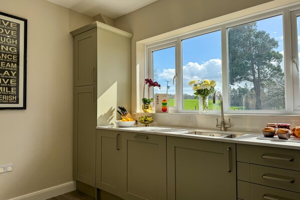 A kitchen with a window, cabinets, and a countertop with kitchenware.