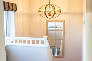 A staircase with a white railing, a hanging light fixture, and a window with a reflection.
