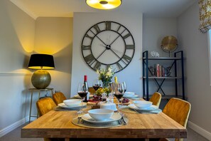 A dining room with a wooden table set for six, surrounded by chairs, with a large wall clock above. - Marrington Lodge, Montgomery , Shropshire (Montgomery)