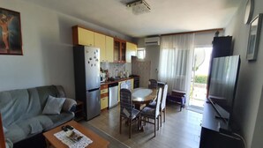 A compact living space with a kitchenette, a dining area, a sofa, and a television. - Spacious Apartment Steps From the Beach, With Private Terrace and Grill (Kastela)