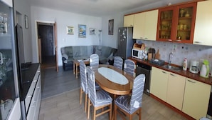 A compact living space with a dining area, kitchenette, and a sofa. - Spacious Apartment Steps From the Beach, With Private Terrace and Grill (Kastela)