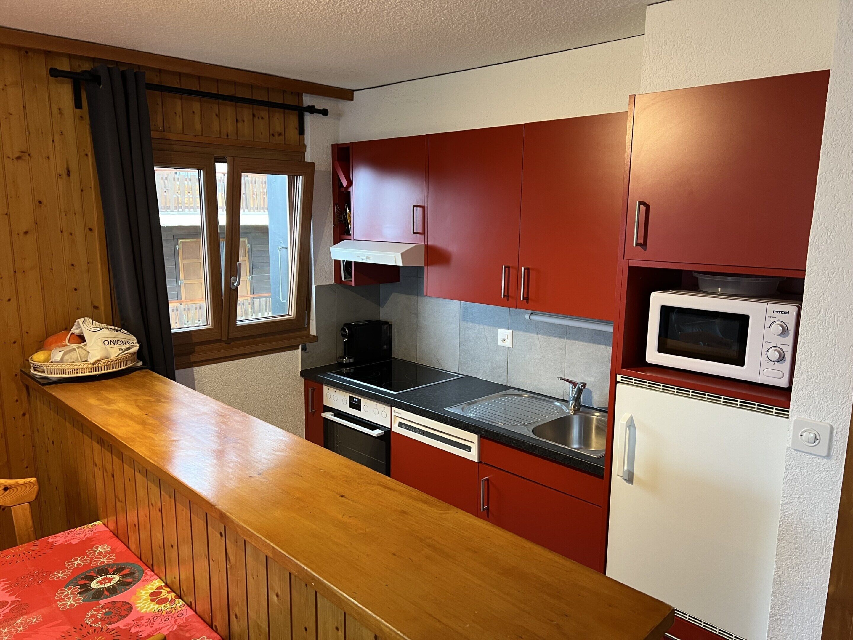 A compact kitchen with wooden cabinets, a microwave, a coffee maker, and a sink.