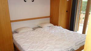 A single bed with a white duvet in a room with wooden flooring and a wooden headboard. - Mystical Apartment With Mountain Views (Veysonnaz)