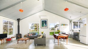 A spacious living area with a fireplace, sofa, and dining table. - Pelican Cottage - Pet Friendly - Wifi (Goolwa North)