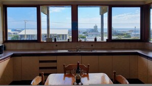 A kitchen with a large window, a sink, and a dining table with chairs.