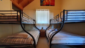 A room with two bunk beds, a small table, and a window with curtains.