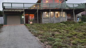 A two-story log cabin with a balcony, a garage, and a well-maintained front yard.