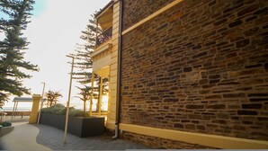 A stone building with a balcony, a paved walkway, and a view of the sea. - Seafield Tower Glenelg Apartment no 6 (Glenelg)