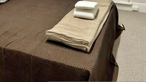 A neatly made bed with a brown patterned bedspread and a beige blanket folded on top. - Seafield Tower Glenelg Apartment no 6 (Glenelg)