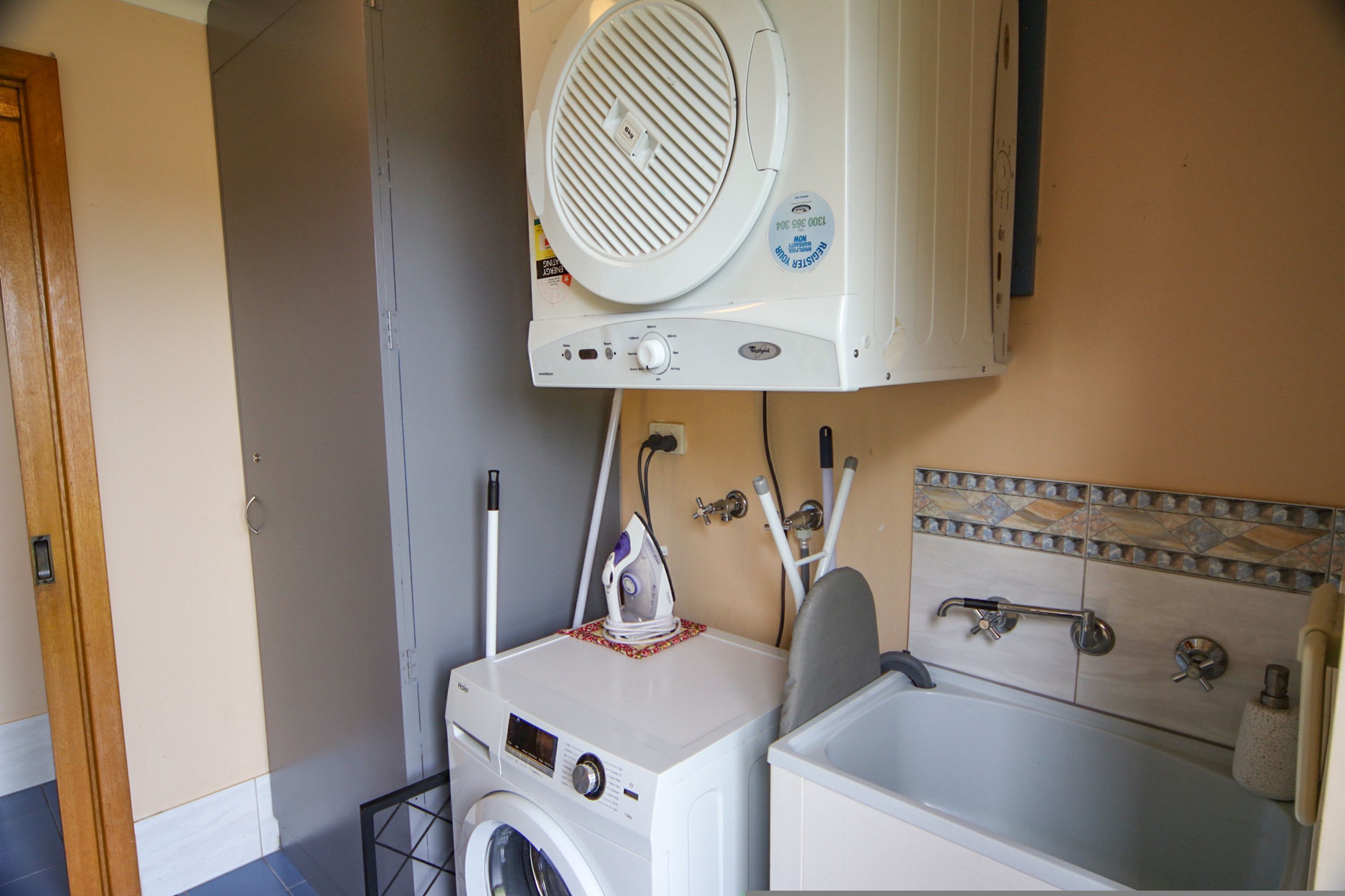 A compact laundry area with a washing machine, dryer, and ironing station.