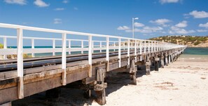 A wooden pier extending into the sea with white railings and a lamp post.