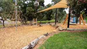 A playground with climbing structures, a shaded area, and a picnic table. - Sandy Pool Shack - Pet Friendly (Seacliff Park)
