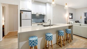 Een moderne keuken met witte kastjes, een centraal eiland met krukken en hanglampen.