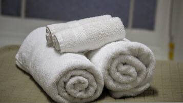 Three neatly rolled white towels stacked on a textured surface.