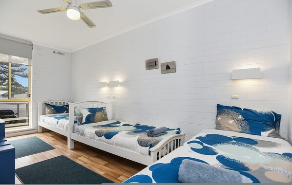 A bedroom with two single beds, a ceiling fan, and a window with a view of the outdoors. - The Dolphins 7 - A View To Remember (Port Elliot)