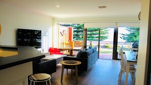 Un espacio habitable moderno con cocina, una mesa de comedor con sillas, un sofá y una mesita redonda.