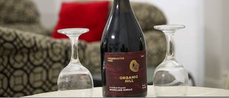 A bottle of Organic Hill sparkling Shiraz wine on a table with two wine glasses.
