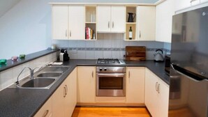 A modern kitchen with white cabinets, a stainless steel refrigerator, and a wooden floor.